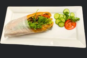 A selection of French fries, mayo, sweet peas, boiled egg, tomatoes, cucumber, cilantro, sauté beef on baguette bread, serve with chips and can soda.