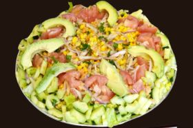 Salad is mixed with sliced avocado, tomatoes, cucumbers, corn, cut lettuce, diced tomatoes, and macédoine. Maison dressing.